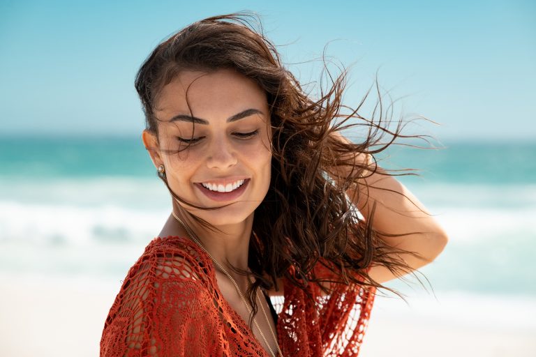 beautiful-latin-woman-enjoying-wind-at-beach-YUD7YYX-768x512